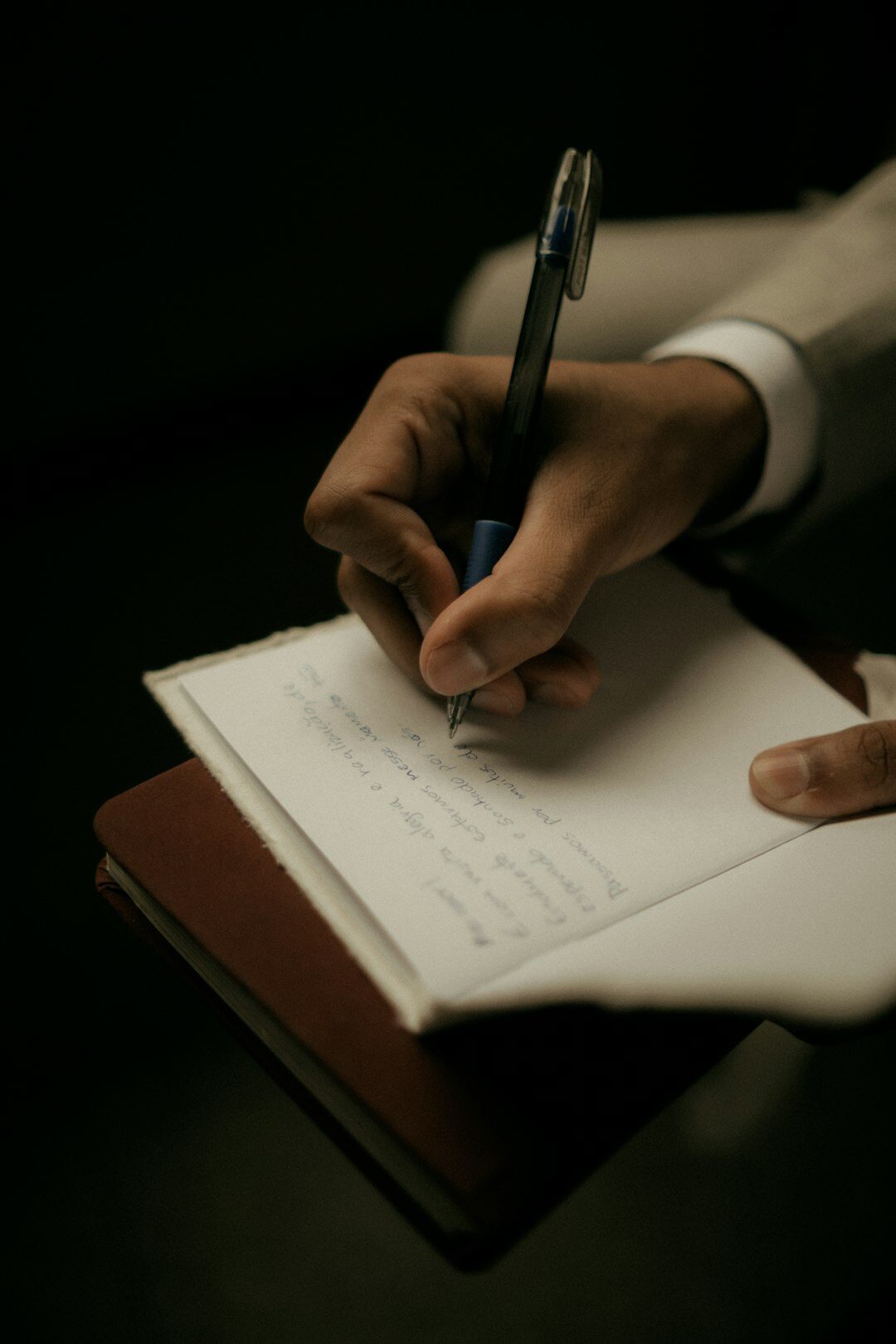 man writing notes in notebook